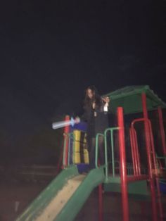 a woman standing on top of a slide at night