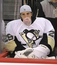 a hockey player sitting on the bench in front of an ice rink with his mouth bubble