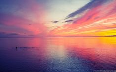 a person is swimming in the water at sunset or sunrise with pink and blue clouds