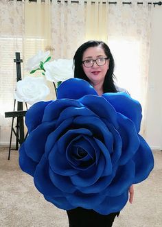 a woman holding a giant blue rose in front of her face