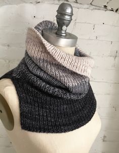 a mannequin wearing a gray and black knitted cowl with the word interest on it