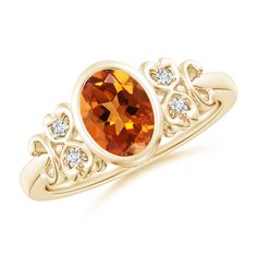 a yellow gold ring with an orange stone and diamonds