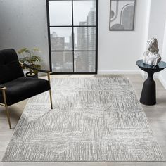 an area rug with grey and white designs on it in a room next to a black chair