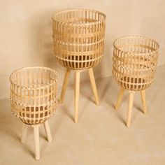 three wicker baskets sitting next to each other on top of a floor in front of a wall