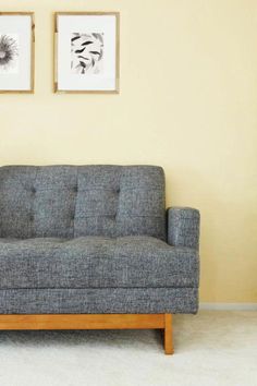 a gray couch sitting in front of two pictures on the wall