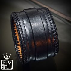 "This Black leather cuff is 2\" wide and hand dyed in a sleek black finish. It is hand braided along the edges with kangaroo lace and also features a hand tooled beveled ridge. A 3/4\" strap is woven through center and closes with leather covered snaps! Custom sized for your wrist! -2\" wide -Vegetable tanned leather -fully lined -Handmade in New York Thanks! Freddie" Leather Cuff Bracelets With Black Band, Adjustable Leather Cuff Bracelet Hand-stitched, Adjustable Black Hand Tooled Bracelet, Adjustable Hand-stitched Leather Cuff Bracelet, Handmade Black Leather Cuff Bracelet, Leather Cuff Bracelet For Formal Occasions, Handmade Custom Leather Bracelet, Formal Leather Cuff Bracelet, Formal Black Leather Braided Bracelets