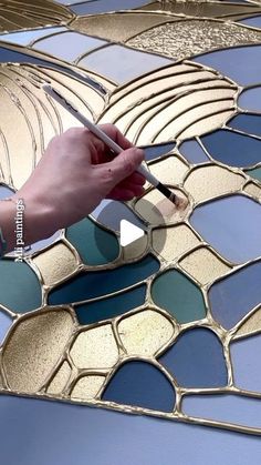 a person is using a pen to draw on a stained glass paneled table top