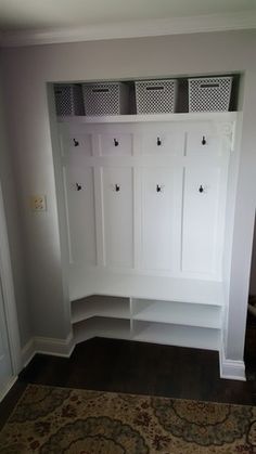 a room with some white cabinets and baskets on the wall next to a carpeted floor