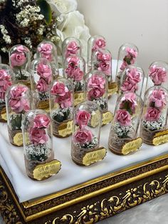 there are many pink roses in glass vases on the table with gold trimming