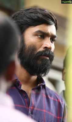 a close up of a person with a beard and wearing a blue checkered shirt