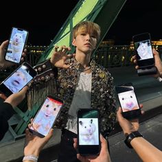 a group of people holding up cell phones in front of them with pictures on them