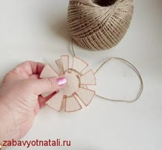 someone is making a flower out of paper and twine with yarn on the table