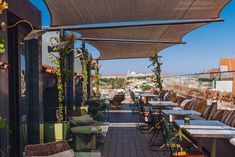 an outdoor dining area with tables and chairs on the roof terrace overlooking cityscape