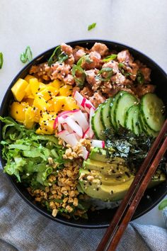 a bowl filled with vegetables and meat next to chopsticks