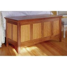 a wooden bench sitting on top of a hard wood floor next to a white bed