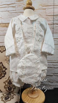 a white dress and bonnet on a wooden stand