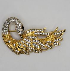 Exquisite Golden Swan Brooch With Diamanté Crystal Rhinestones Black Enamel Eye Authentic Collectible Vintage Luxury Costume Jewelry... This Elegantly Sparkling Golden Swan Beauty is Artfully Designed with Flowing lines, a Truly Graceful Figural piece Beautifully Well Crafted in a Richly Textured Gold Tone finish with an Abundance of Sparkling Diamanté Crystal rhinestones. The Meticulously Detailed Sculptural Design Creates Incredible Depth. With it's Chic Black Enamel Eye, Long Arched Neck and Lushly Feathered Body it Evokes the Wonderfully Calming Sense of Gracefully Gliding Fluid Movement. An Exquisitely Romantic Swan Brooch to Adore Wearing from Your Well Curated Jewelry Collection or to Give as an Beautiful Vintage Jewelry Present. This Rich Graceful Golden Swan Beauty measures approx Swan Beauty, Swan Brooch, Fluid Movement, Artfully Designed, Gold Texture, Jewelry Lover, Black Enamel, Crystal Rhinestone, Costume Jewelry