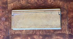 an old metal box sitting on top of a wooden table with wood grained walls