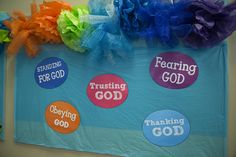 colorful bulletin board with sayings on it and ribbons hanging from the wall above them