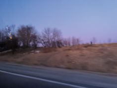 a blurry photo of the side of a road with trees and bushes on it