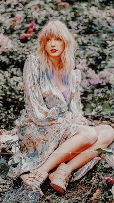 a woman sitting on the ground surrounded by flowers