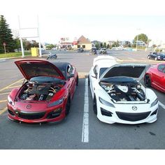 two cars parked in a parking lot with their hood open