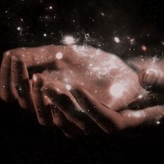 two hands holding each other in front of some stars and light up the night sky