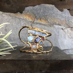 This collection was inspired by the unique ecosystems of the ocean and the significance of flora and fauna. Vastly different species rely on one another in order to thrive in their shared environment. Kyanite, aquamarine, tanzanite, ruby, labradorite, emerald, rose quartz and grossular garnet are all embedded in brass and come together in perfect harmony. This cuff is slightly adjustable and can be gently squeezed. Length 1 1/2" in Diameter 2 1/2" Cuff Opening 1" This piece is handmade-to-order, Garnet Stone Jewelry, Grossular Garnet, Life Aquatic, By The Ocean, Quartz Jewelry, Funky Jewelry, Garnet Stone, Perfect Harmony, Rough Gemstone