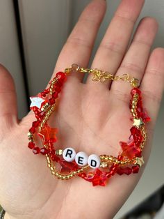 a hand holding a red beaded bracelet with the word read spelled in small letters