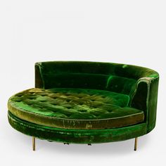 a green round couch sitting on top of a wooden table next to a white wall