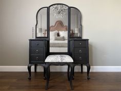 a bedroom with a vanity, mirror and stool on the hardwood floor in front of it