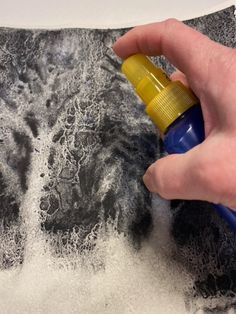 a person is spray painting on a piece of paper with black and white inks