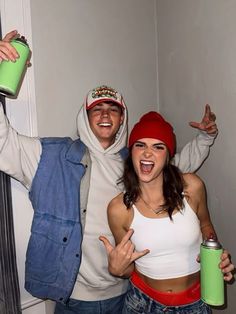 two people dressed in costumes posing for the camera with one holding a green can and another wearing a red hat