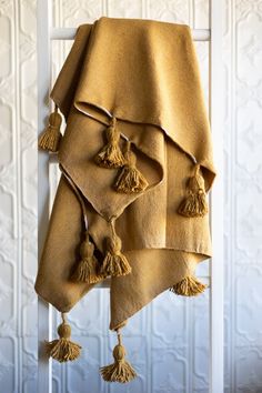 three towels hanging on a ladder with tassels in front of a white wall