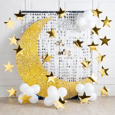 the moon and stars are next to balloons in front of a white wall with gold foil