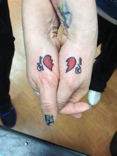 two people with tattoos on their hands holding each other's fingers and one has an arrow