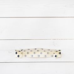 a white wooden wall with a blue flowered tie bar on it's end