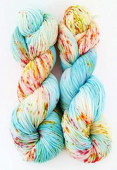 three skeins of yarn with multicolored speckles on white background