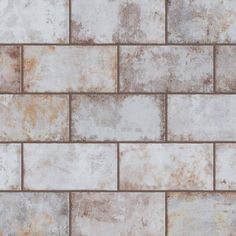 a white and brown brick wall with rusted metal grates on the bottom half