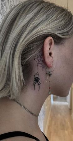 a woman with a spider tattoo on her neck and behind her ear, looking into the distance