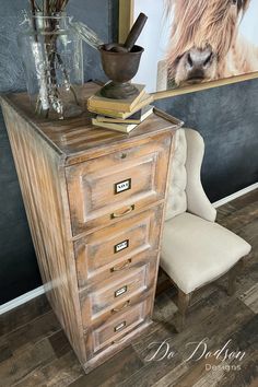 a wooden dresser with drawers and a vase filled with flowers on top of it next to a chair