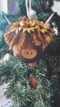 an ornament hanging from a christmas tree decorated with flowers and a cow's head