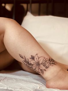 a woman laying on her stomach with a flower tattoo on her leg