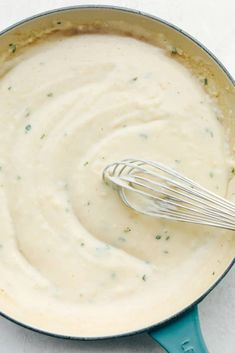 a pot filled with cream sauce and a whisk in the bottom right hand corner