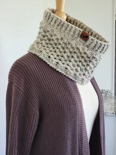 a woman wearing a knitted cowl neck scarf on top of a mannequin