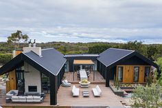 an aerial view of a modern house with outdoor furniture in the foreground and trees on the other side