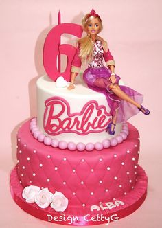 a barbie doll sitting on top of a birthday cake with the number six in pink