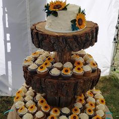 three tiered cake with sunflowers and cupcakes on the bottom layer