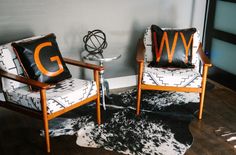 two chairs sitting next to each other on top of a hard wood floor covered in black and white rugs