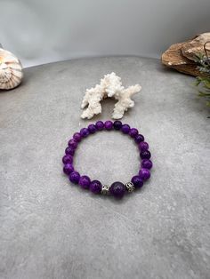 Elevate your style and spirit with this stunning Sugilite and Amethyst gemstone bracelet. Handcrafted with love and care in Port Saint Lucie, Florida, this bracelet features the soothing energies of Sugilite paired with the calming properties of Amethyst. Let this bracelet serve as a reminder of your beachside adventures, with two silver spacers adding a touch of elegance. Whether you're strolling along the shore or attending a special event, this stretch bracelet is the perfect accessory. Harne Spiritual Amethyst Bracelets In Purple, Purple Natural Stone Beaded Bracelets For Meditation, Purple Natural Stones Beaded Bracelets For Meditation, Purple Gemstone Beads Bracelets For Healing, Spiritual Amethyst Purple Bracelets, Purple Beaded Bracelets With Natural Stones For Meditation, Purple Beaded Bracelets With Natural Stones For Healing, Spiritual Purple Crystal Bracelet With Natural Stones, Healing Purple Bracelets With Natural Stones